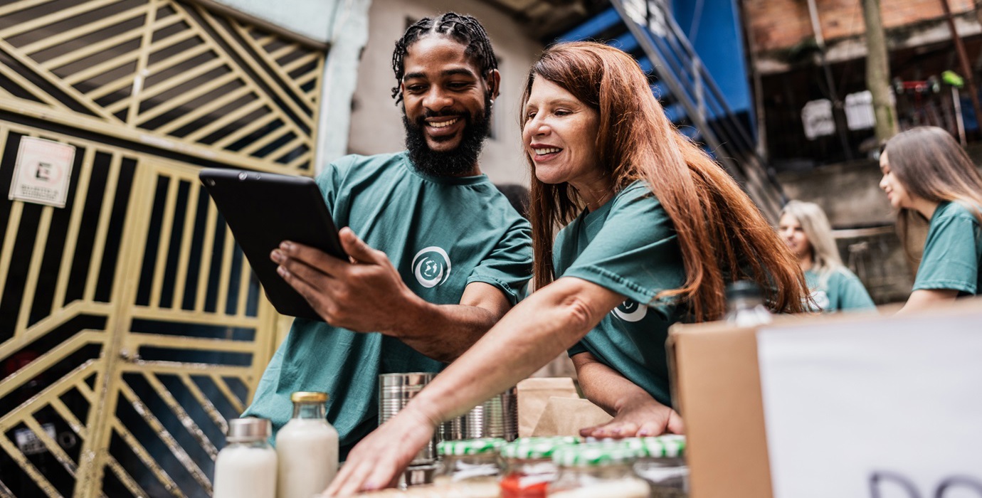 Two volunteers track donations on a tablet.