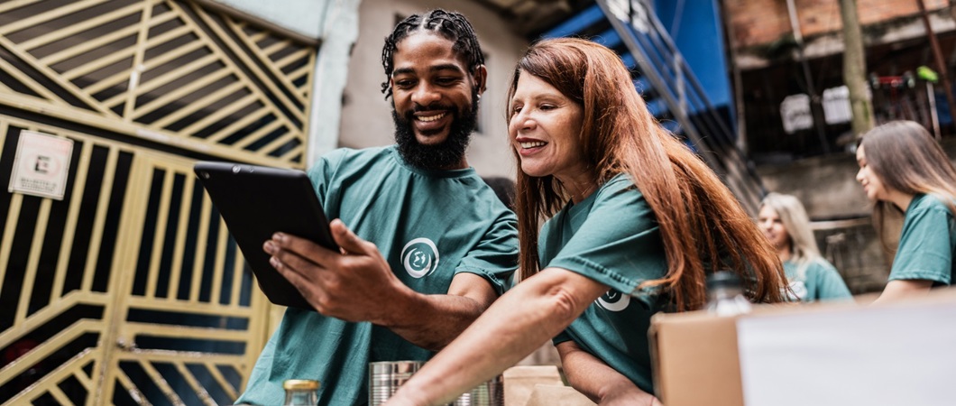 Two volunteers track donations on a tablet.