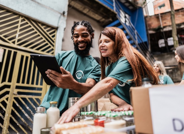 Two volunteers track donations on a tablet.