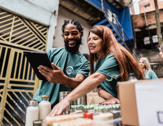 Two volunteers track donations on a tablet.