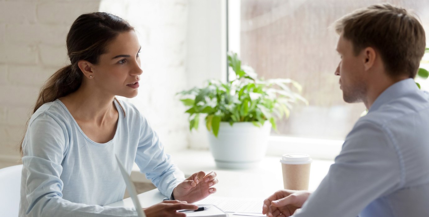 Coworkers talking at a table in the office.