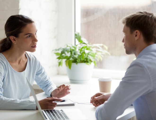 Coworkers talking at a table in the office.