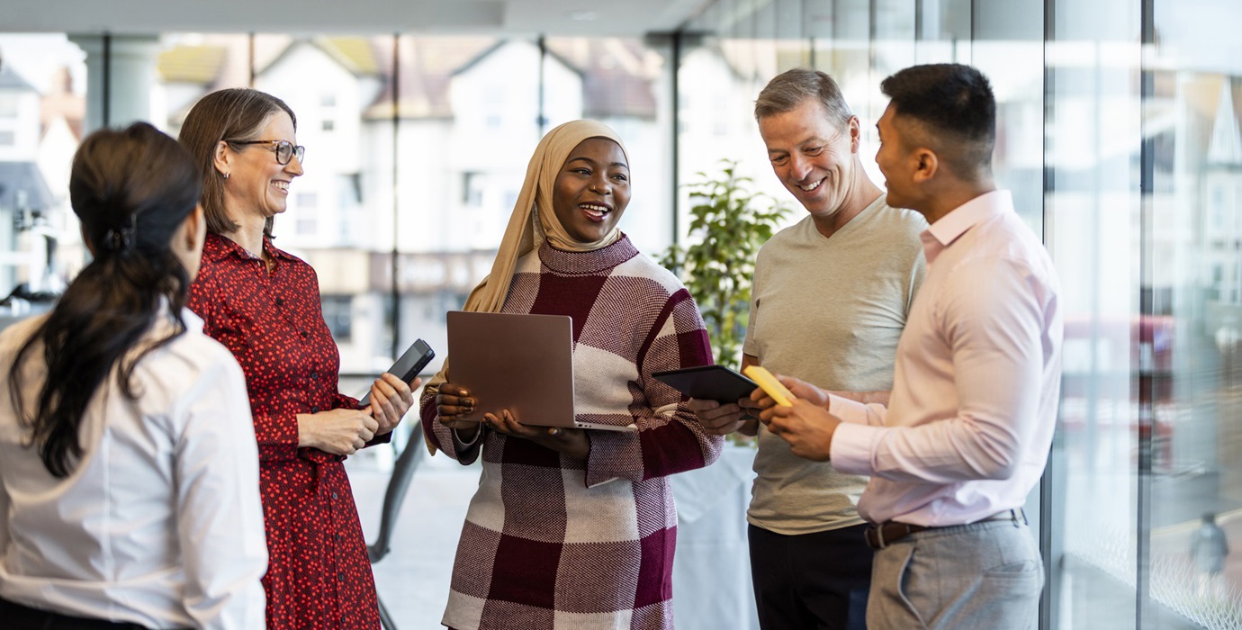 A group of young and mature office workers standing together to talk about work. 