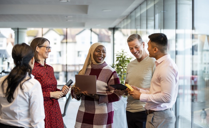 A group of young and mature office workers standing together to talk about work.