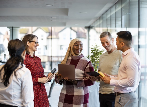 A group of young and mature office workers standing together to talk about work.