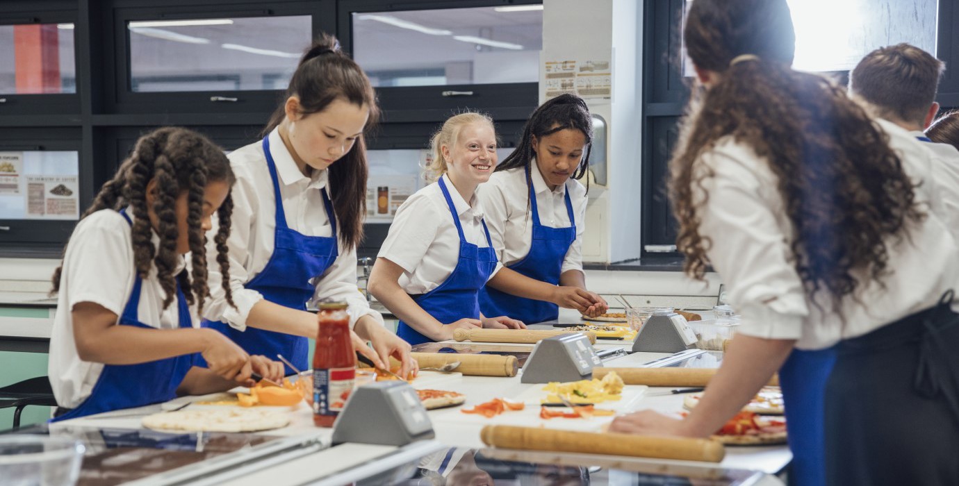 High school students making pizza in cooking class.