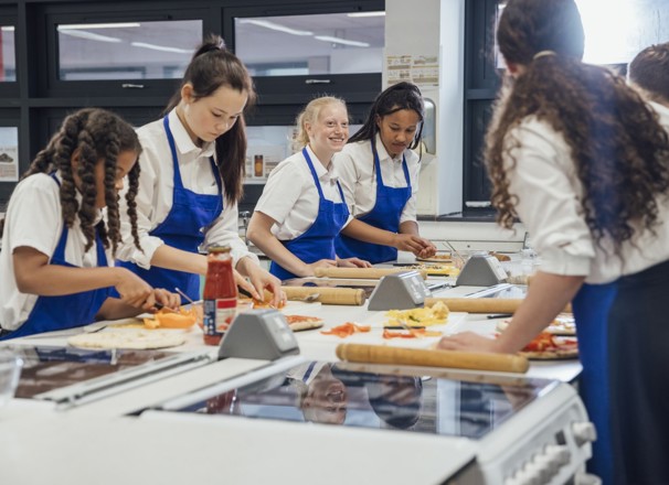High school students making pizza in cooking class.