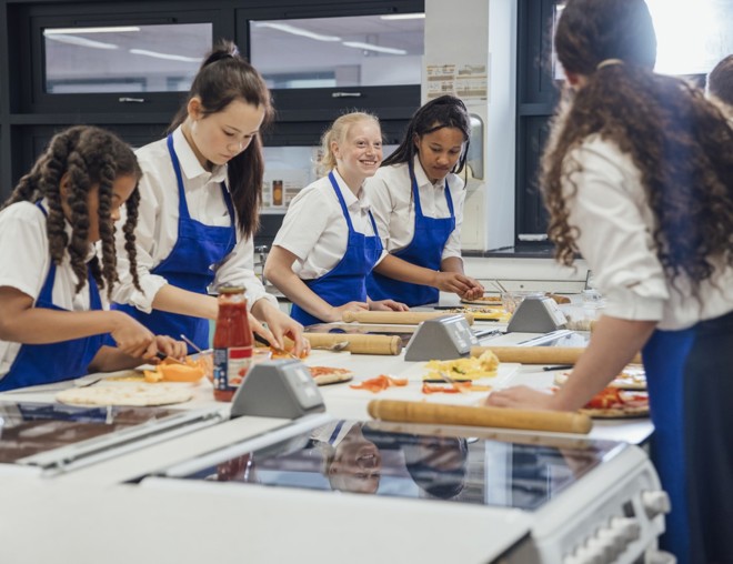High school students making pizza in cooking class.