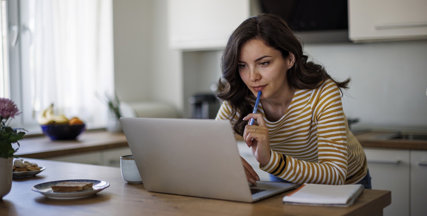 Person using laptop while standing over kitchen counter.