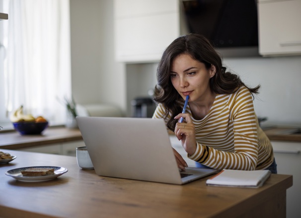 Person using laptop while standing over kitchen counter.