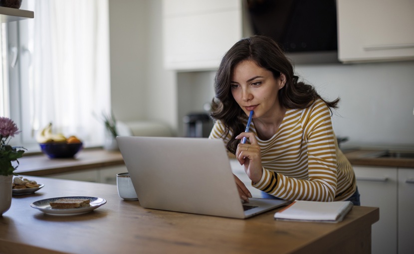 Person using laptop while standing over kitchen counter. 