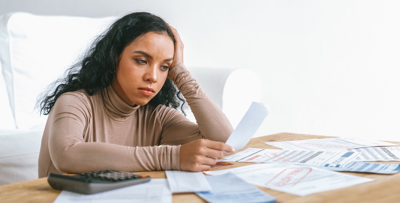 Person looking stressed while looking over a table of bills and receipts.