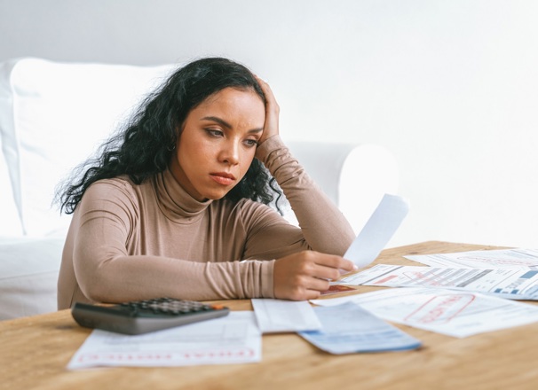 Person looking stressed while looking over a table of bills and receipts.