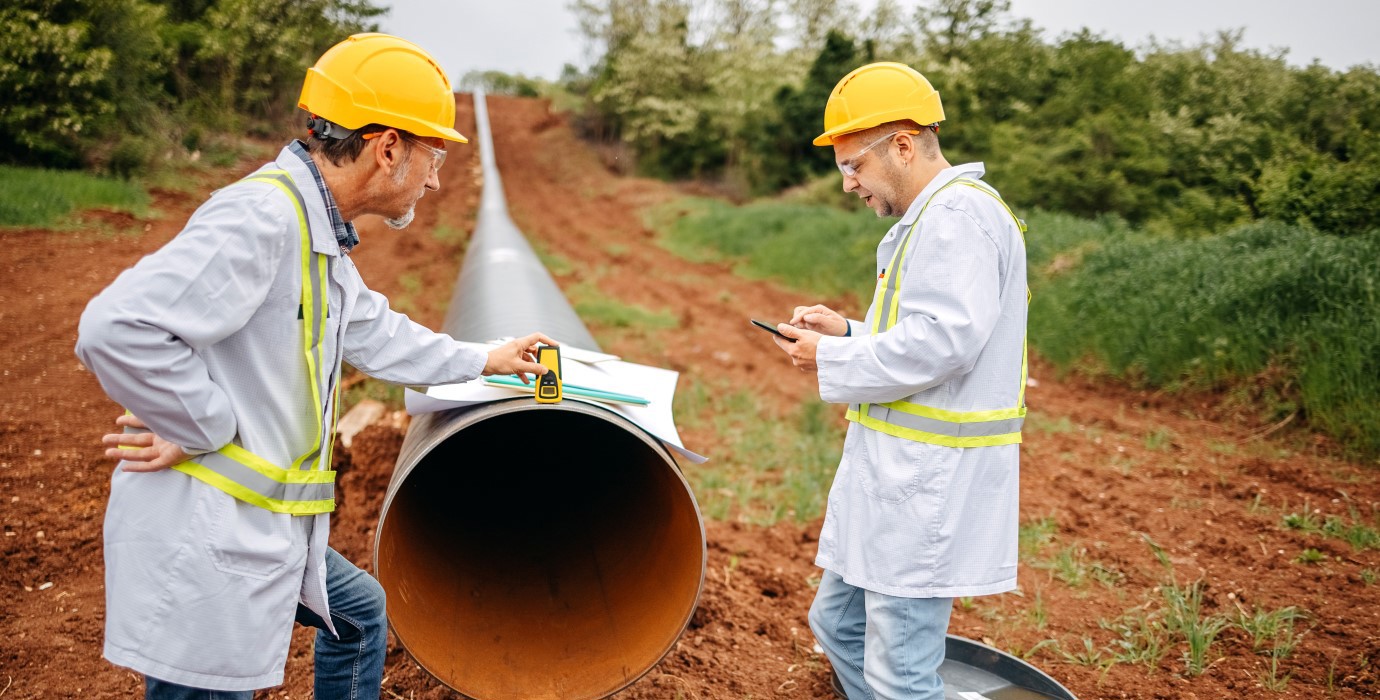 2 engineers inspect a gas pipeline. 