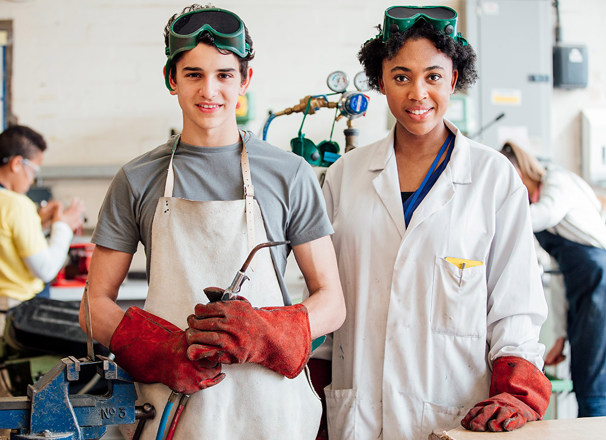 Student and teacher standing with welding gear in class.