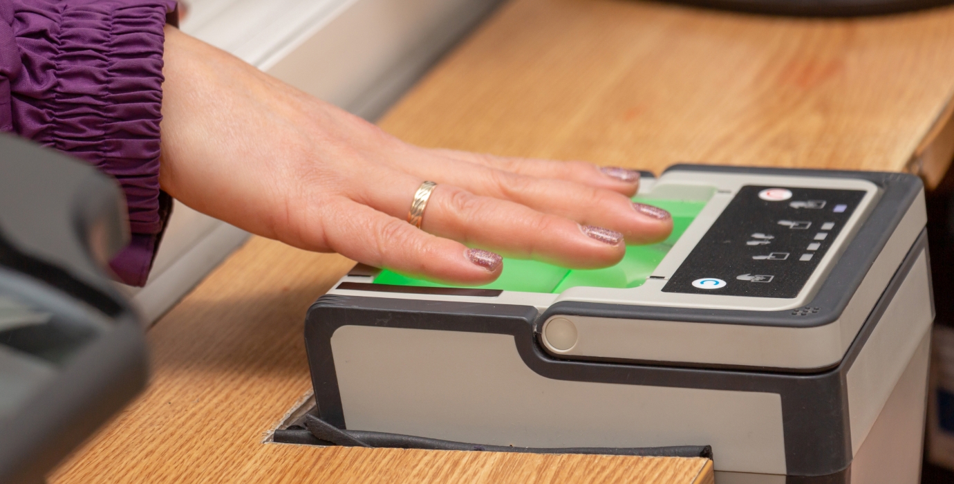 Person with hand placed on a digital fingerprint scanner. 