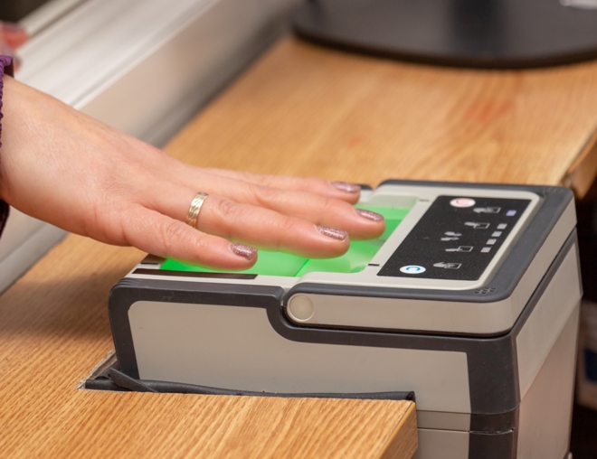 Person with hand placed on a digital fingerprint scanner. 