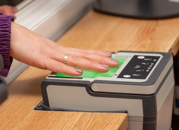 Person with hand placed on a digital fingerprint scanner. 