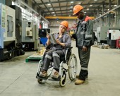 Two employees in a manufacturing shop review information on a tablet.