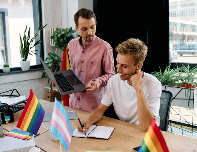2 colleagues working at desk with transgender and pride flags
