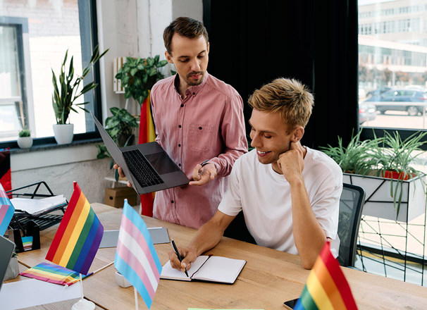 2 colleagues working at desk with transgender and pride flags