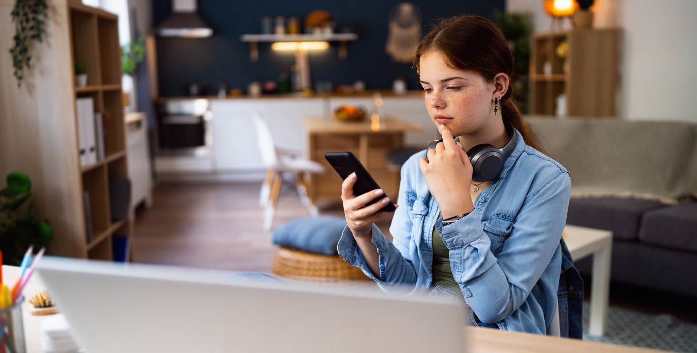 Teenager looking thoughtfully at smartphone.