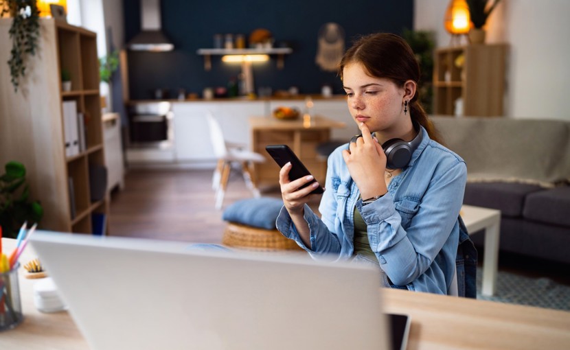 Teenager looking thoughtfully at smartphone.
