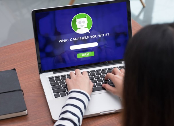 Person typing a question into a chatbot on a laptop.
