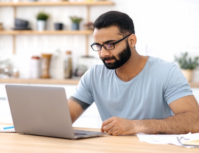 Person looking at laptop while sitting at desk. 