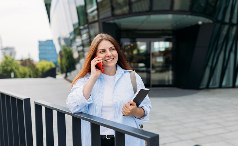 Person with ipad outside office building on phone