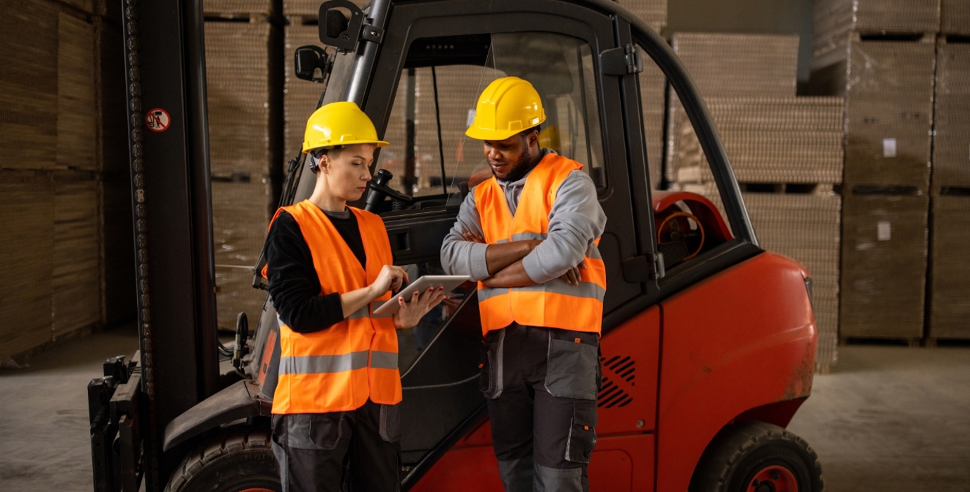 Person training coworker to use a forklift in a warehouse.
