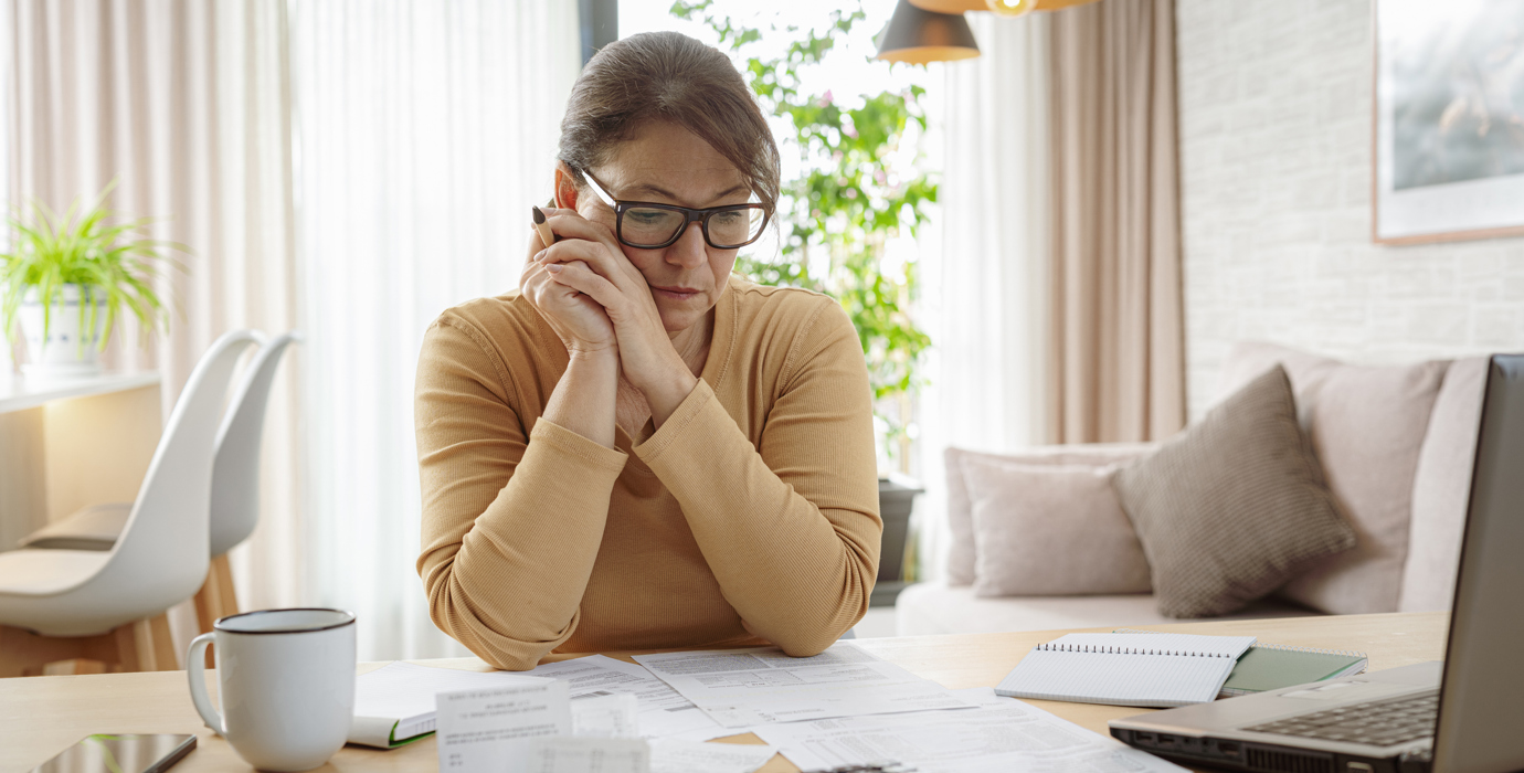 person looking at bills on their table while looking very focused