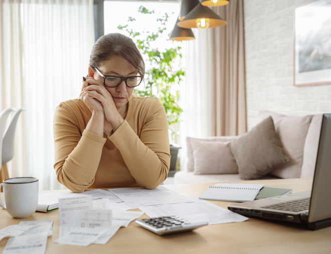 person looking at bills on their table while looking very focused