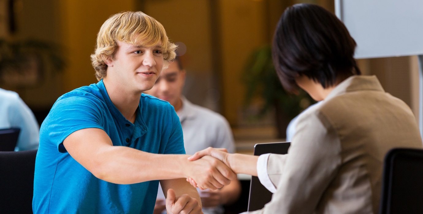 Teen shakes an interviewer's hand at a job interview.