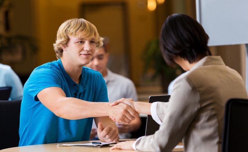 Teen shakes an interviewer's hand at a job interview.