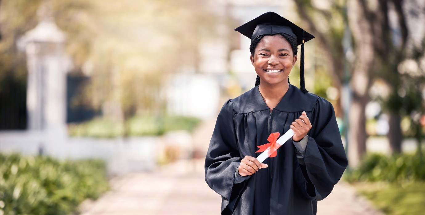 Student posing in cap and gown on high school graduation day. 