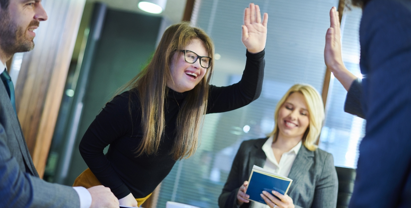 Coworkers high-five each other over a conference room table. 