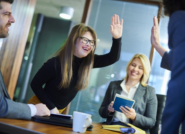 Coworkers high-five each other over a conference room table. 