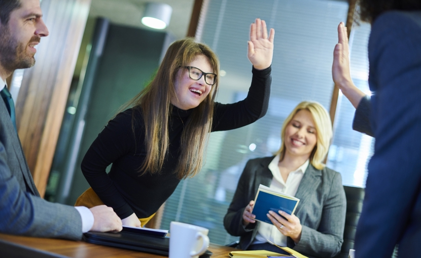 Coworkers high-five each other over a conference room table. 